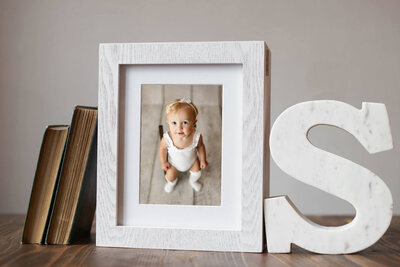 white wooden display box with toddler photo in front on tables with books leaning against it
