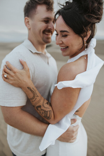 Engaged couple smiling on beach together for engagement shoot