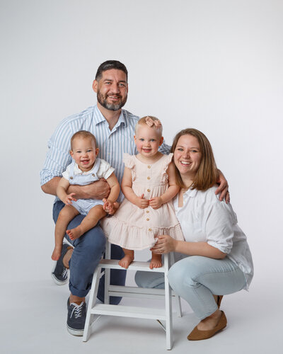 Family portrait of four with young children taken on a white background