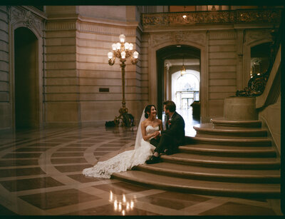 bride and groom sitting on stairs embracing 