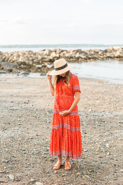 pregnant woman wearing a straw hat looking at her belly