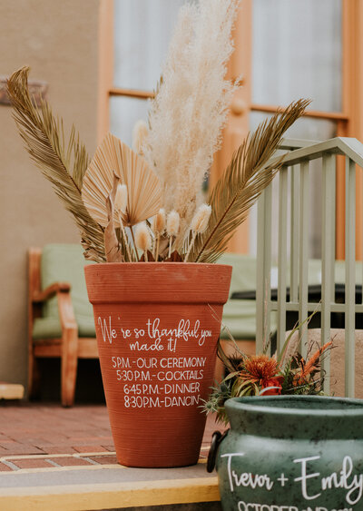 Wedding day welcome sign and program sign on garden pots.