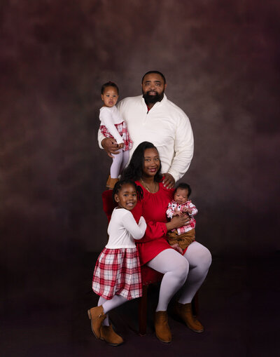 family-of-five-in-red-posing-in-studio-with-new-baby