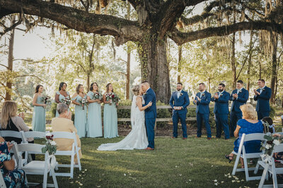 Bride and groom kissing beneath large tree in hilton head