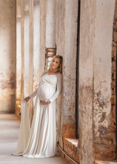 Pregnant mom in white maternity gown at The Providence Cotton Mill in Maiden, NC.