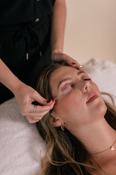 Woman laying down while medspa practitioner gives her eyelash treatment