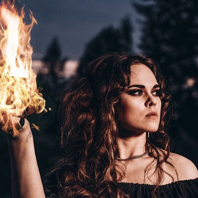 girl with long curly hair holding ball of fire in hand