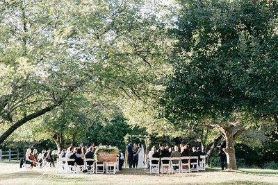 A bride and groom with a rustic wooden arch above them. The beautiful outdoor wedding took place at John James Audubon Center. Wedding Officiant Lehigh Valley Celebrants.