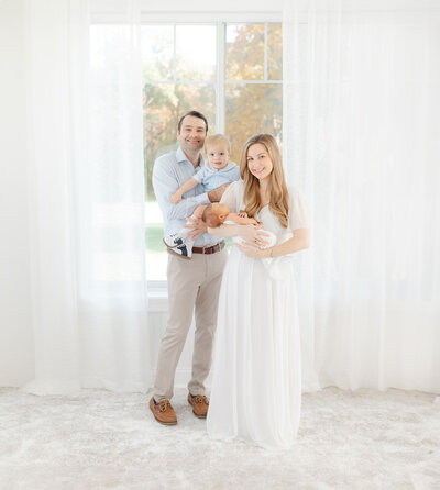 mom holds newborn baby and dad holds toddler during boston newborn photography session