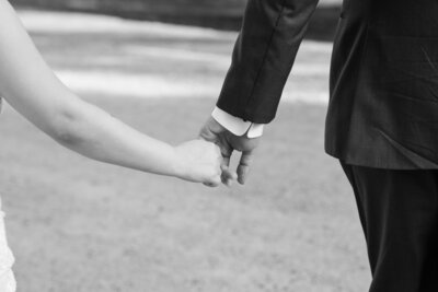 Austin-based wedding photographer captures stunning black and white photo of a bride and groom holding hands.