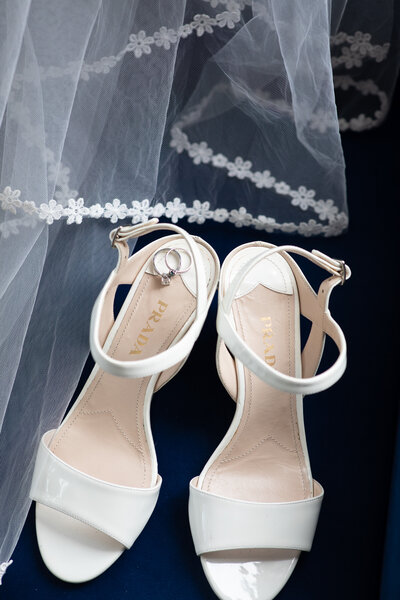A pair of white wedding shoes with a veil captured beautifully by an Austin-based wedding photographer.