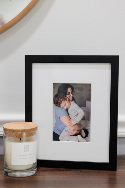 A framed photo of a mom holding her toddler in bed