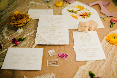 Jackson Hole photographers capture burlap, lace, and flowers for wedding flatlay with wedding invitations rings and more