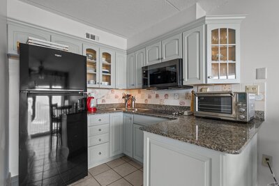 Modern kitchen at 222 Carolina Beach featuring granite countertops, light gray cabinets, and black appliances