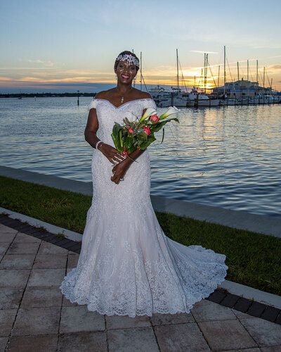 a woman in a bridal dress posing with flowers for her bridal portrait in front of the Sarasota bay.