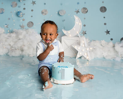 Little boy eating cake on a blue background.
