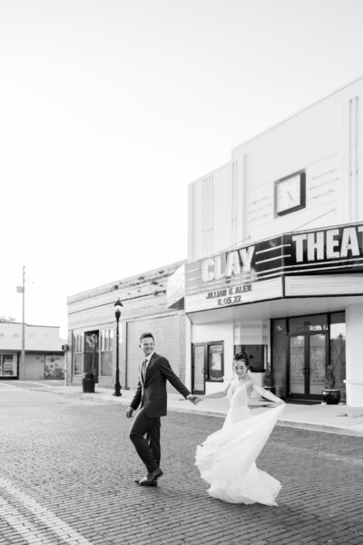 A wedding couple in an editorial black and white walking on the street at the Clay Theater by Florida wedding photographer Angelika Krug Photo & Film