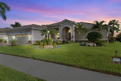 gray tropical home with lights on with green lawn taken during sunset