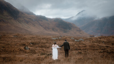 embracing couple at base of mountain in glencoe during elopement
