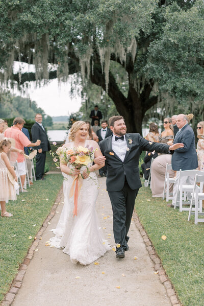 Bride and groom just married walking down the aisle to flower petals at Middleton Place under the oak