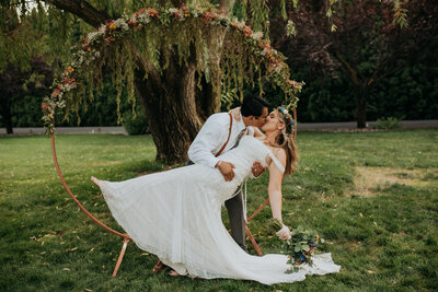 bride and groom celebrate wedding at promise gardens in pasco, washington in front of arch