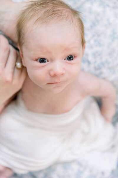Image of newbor baby held by mother close up with eyes wide open taken by Sacramento Newborn Photographer Kelsey Krall Photography