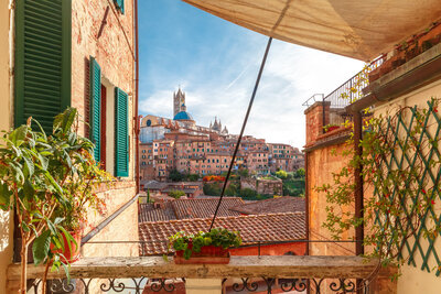 Old Town of medieval city of Siena in the sunny day through autumn leaves
