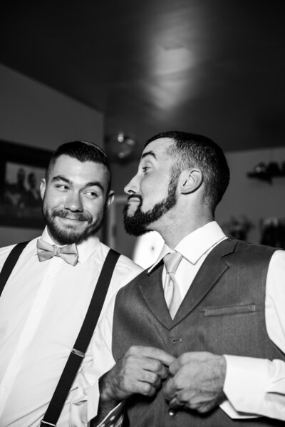 Two men smiling at each other ass they get ready for a wedding