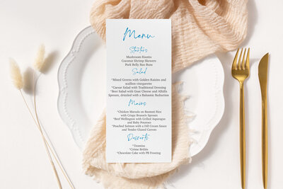 Wedding menu sitting on apricot colored napkin on a plate