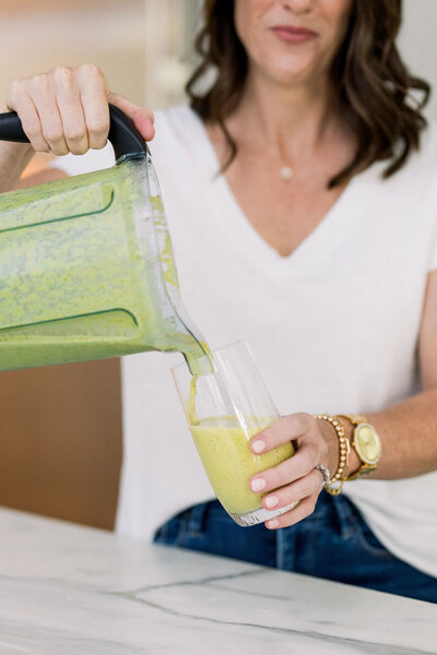 Lara Murrant pouring a green smoothie from a blender