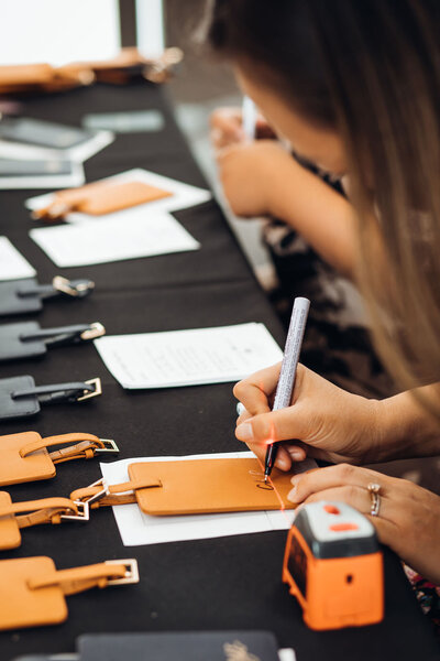 Corporate event activation, writing live calligraphy on luggage tags