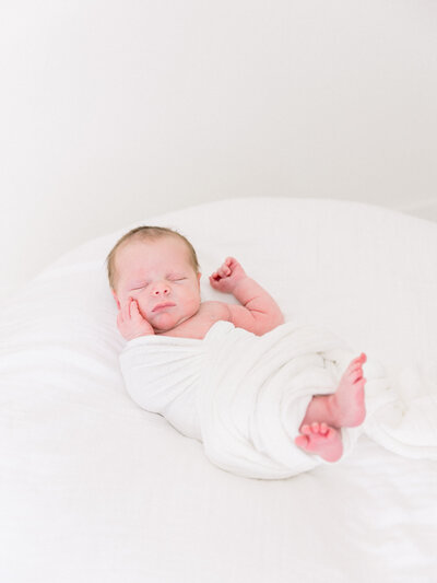 Image of sleeping baby wrapped in white with hands up taken by Newborn Photographer Sacramento Kelsey krall
