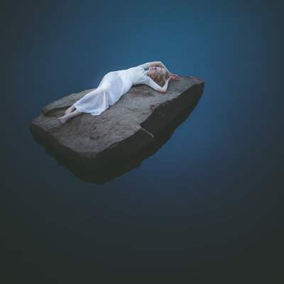 Fine Art Work of a woman lying on a stone in the water