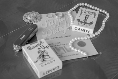 Vintage-inspired wedding invitation flat lay with rings, candy boxes, and pearls – photographed by wedding photographer Niko Coric – Lumen Clarity Media