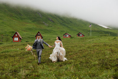 bride and groom standing on top of black rocks with a lake and trees in the background