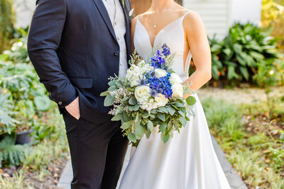 Stunning bride and groom pose for portrait on their wedding day holding wedding bouquet