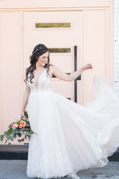 Bride lifts up a piece of her wedding dress skirt and lets it fall gracefully