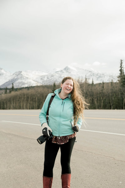 woman smiling with camera by rocky mountains