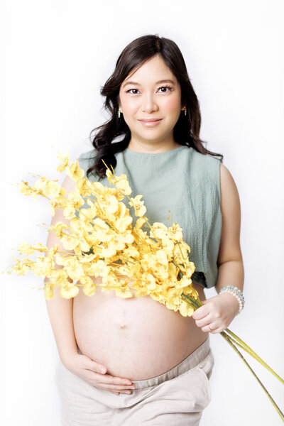 maternity photoshoot holding a yellow flower