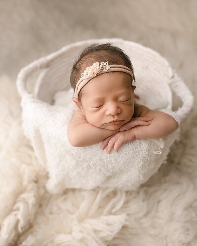 baby girl in basket on white rug for portland newborn pictures
