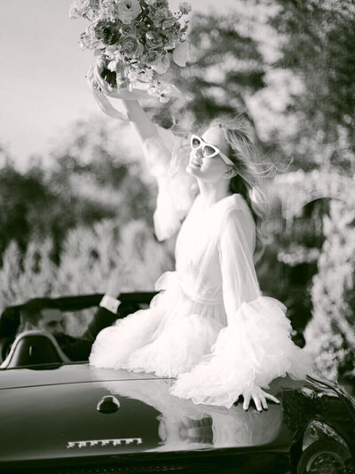 Black and white bride sitting on convertible car with sunglasses