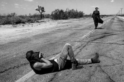 On Location Behind the Scenes Photo Mark MAryanovich lying on road in desert photographing Leslie Cours Mather