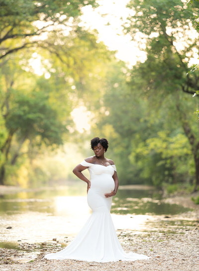 woman wearing white fitted maternity dress standing in a creek