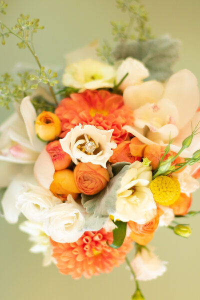 beautiful wedding ring nestled in yellow and orange wedding bouquet