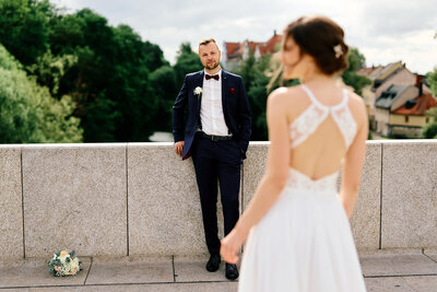 Ein Brautpaar steht sich auf der Steinernen Brücke in Regensburg gegenüber. Die Braut sieht nach links während der Bräutigam stolz zur Braut sieht.
