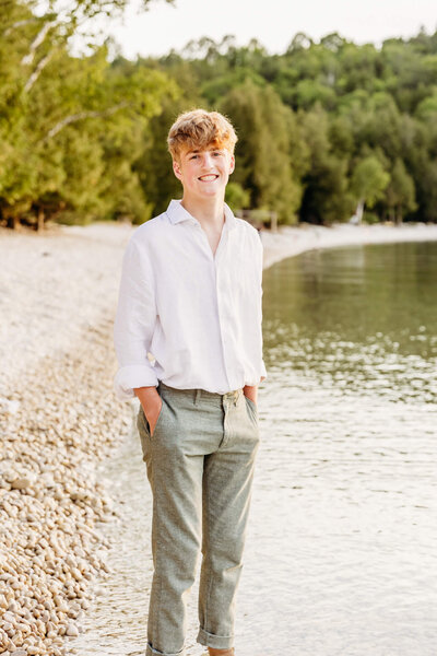 senior boy standing in the lake and smiling for high school portrait session