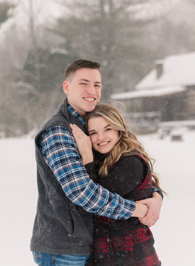 young man and woman embracing and looking at the camera in the snow