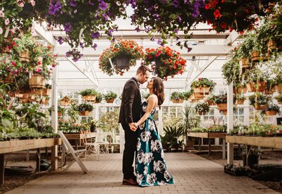 Couple embraces for engagement photograph in a greenhouse filled with light