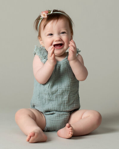 Six month old baby girl claps and smiles during her studio photo session with Laura King Photography