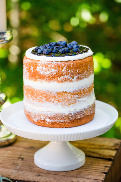 A delicious bare cake with blueberries on top